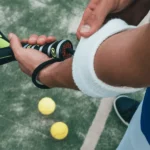 Photo provenant de Canva d'un homme s'équipant de deux balles, une raquette et un bandeau de pignet pour jouer au padel